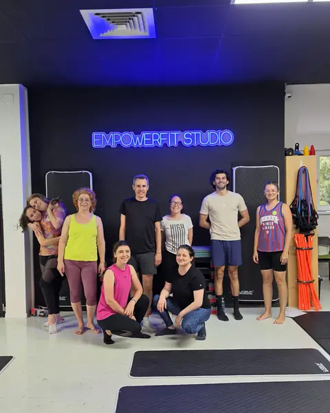 Participanții la un workshop, în fața logo-ului EmpowerFit Studio