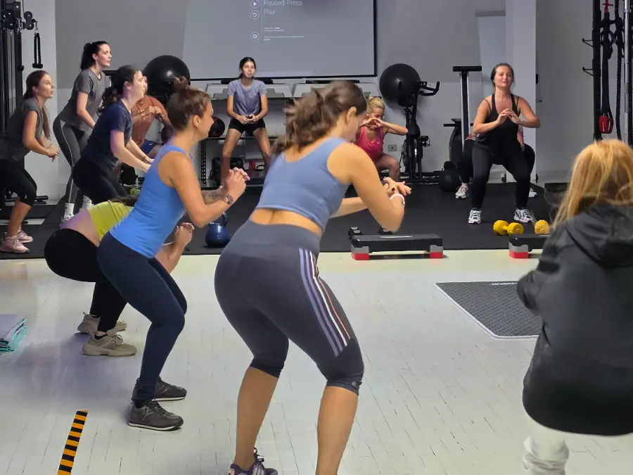 Membre EmpowerFit care fac genuflexiuni la o clasă de aerobic în studio